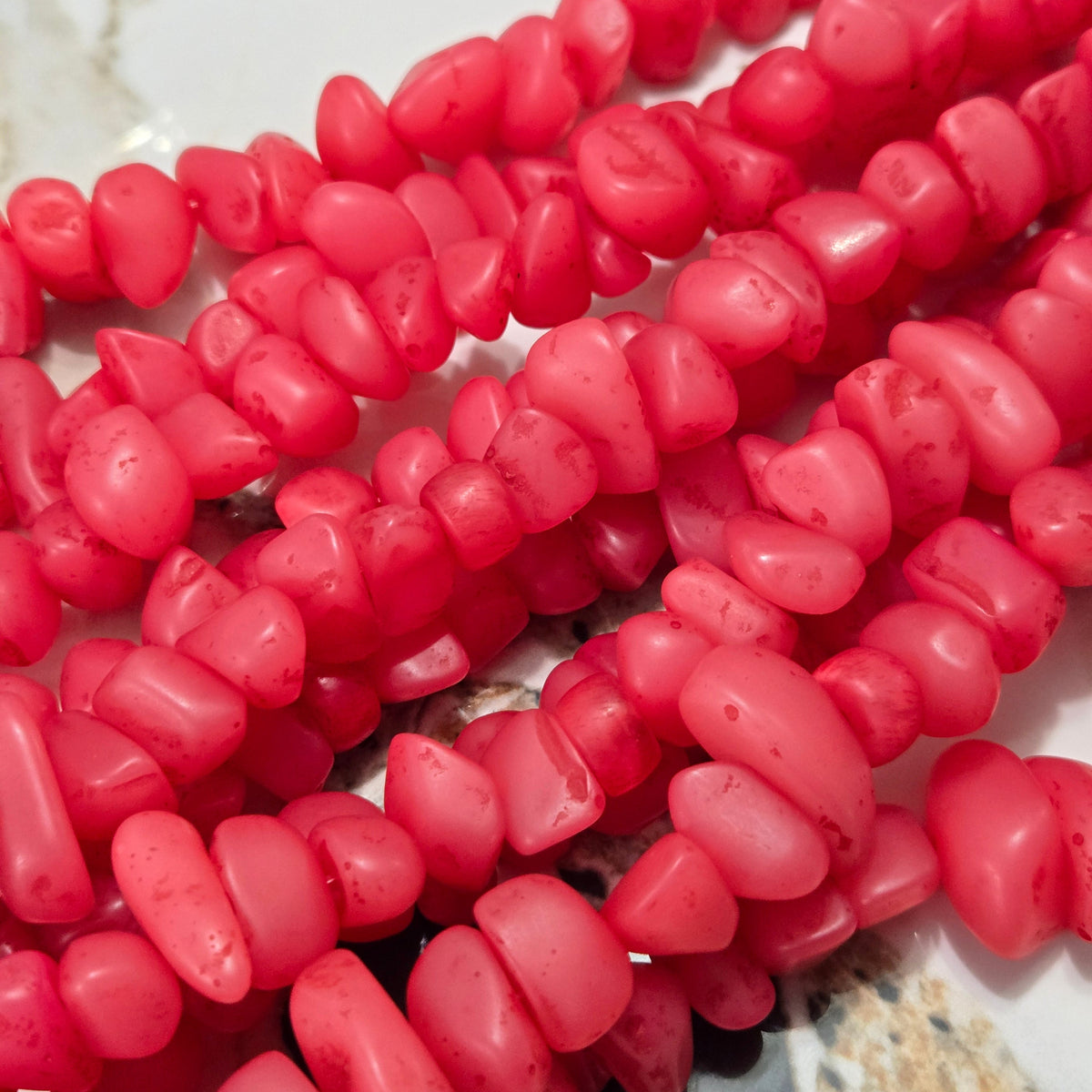 Pink resin chip bead strand with faceted irregular pieces