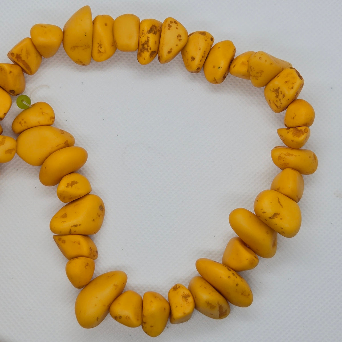 Yellow resin chip beads strand formed into a loop, irregular chips with speckles