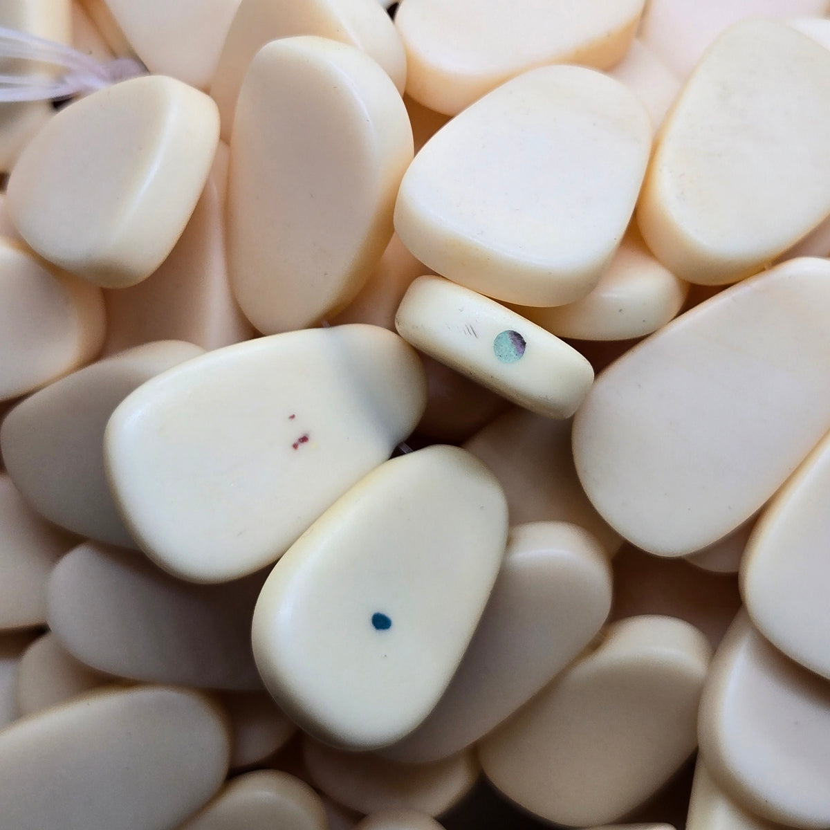 Beige teardrop resin beads with smooth surfaces, few visible specks on some pieces