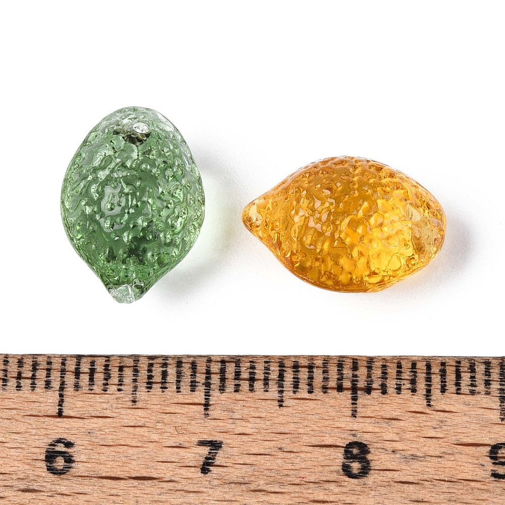 Glass beads with hole, green and amber translucent teardrops beside ruler