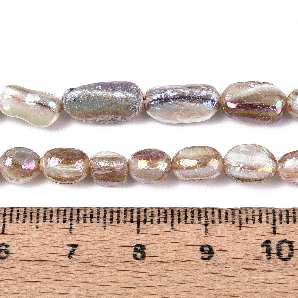 Electroplated shell nugget bead strand with small tan oval beads beside a ruler