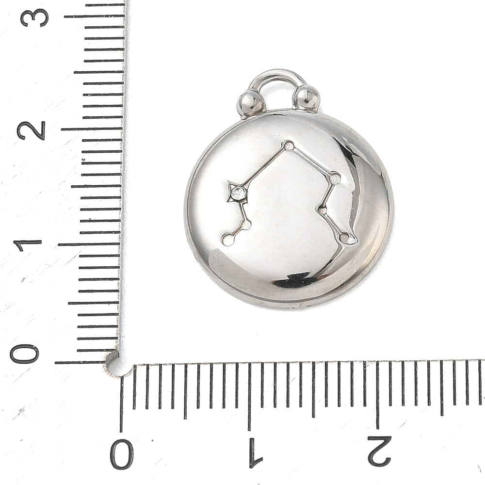 Silver round Libra zodiac charm pendant next to a measuring ruler for size reference
