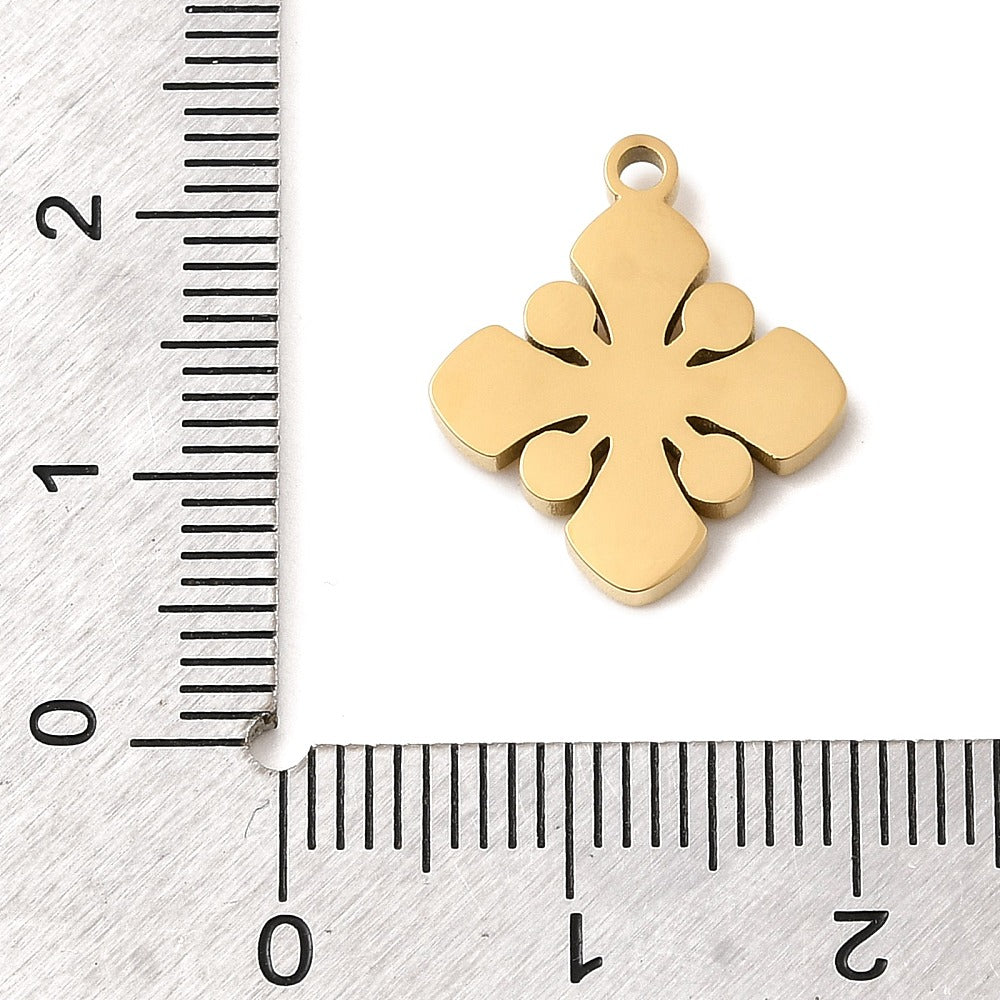 Gold-plated flower charm with rhinestones beside metric ruler for scale