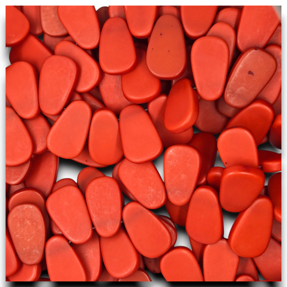 Red flat teardrop resin beads strand close-up, smooth matte teardrop shapes