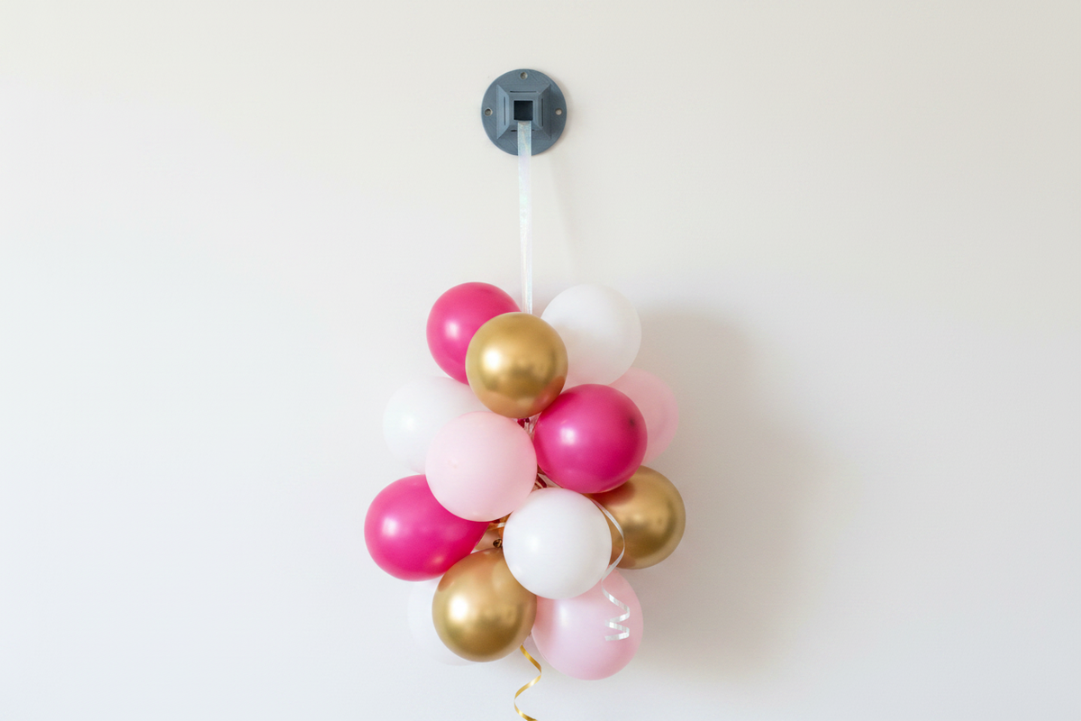 Round plastic wall anchor with clear string loop; holds pink and gold balloon cluster