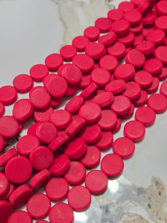 Red flat rondelle resin beads, close-up of glossy discs