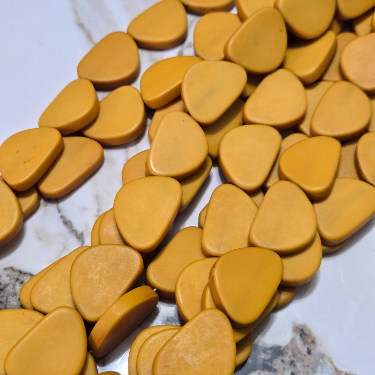 Mustard yellow flat resin triangle beads, close-up of individual shapes