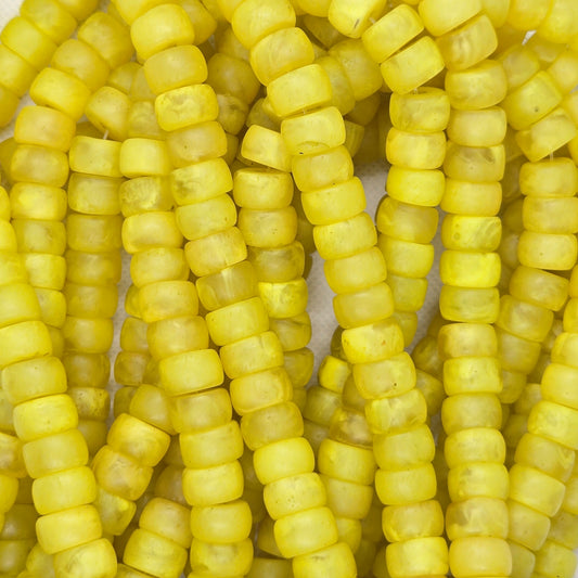Yellow rondelle resin beads close-up, cylindrical segments on a strand.