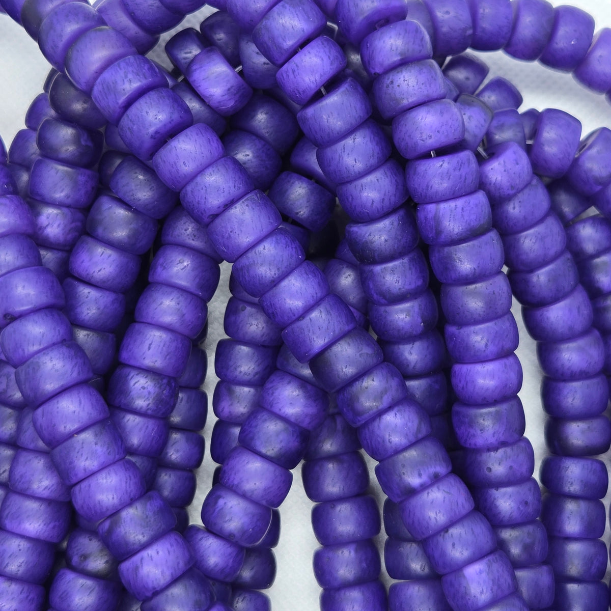 Close-up of purple rondelle resin beads, small rounded discs