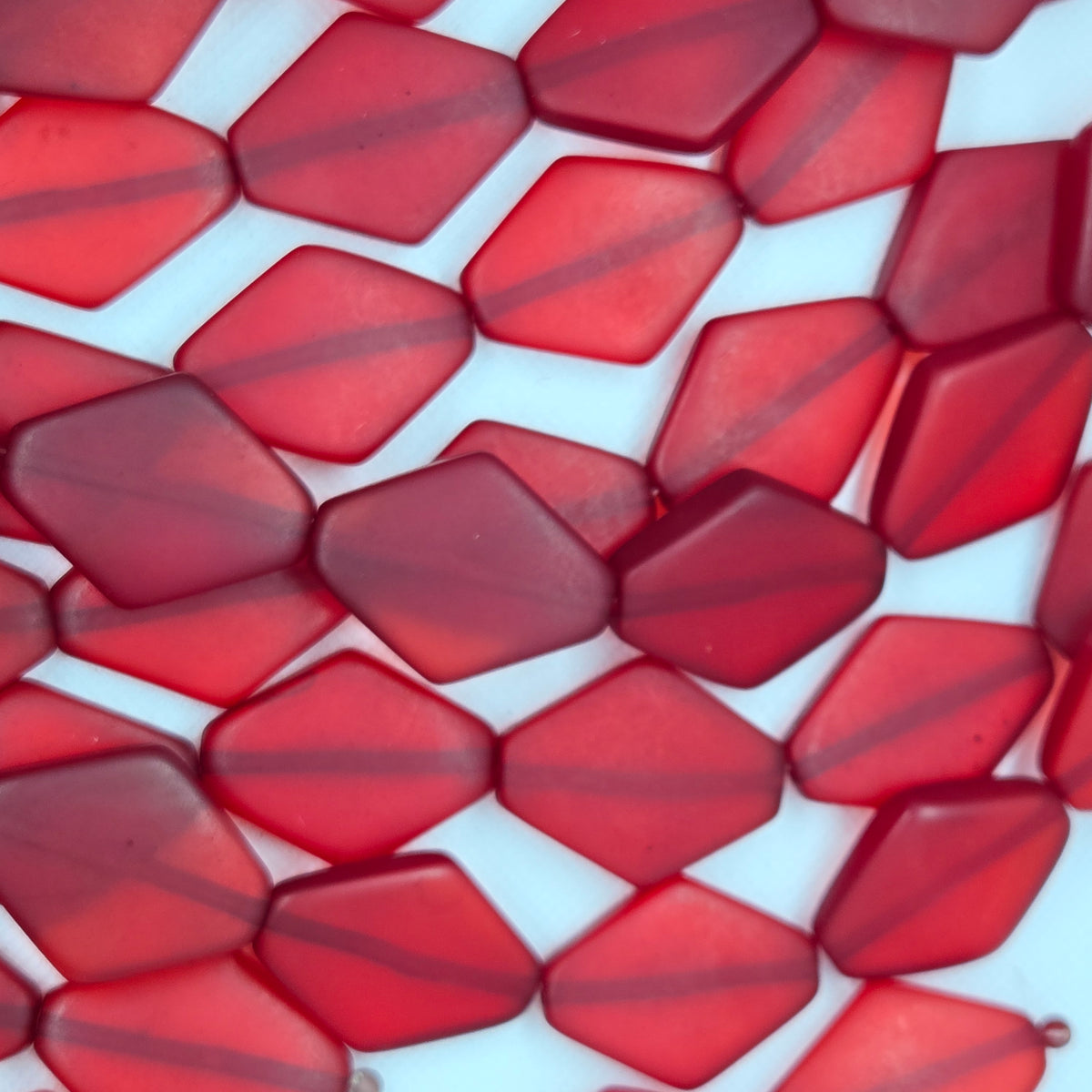 Diamond-shaped resin beads, deep red, faceted geometric pattern in close-up