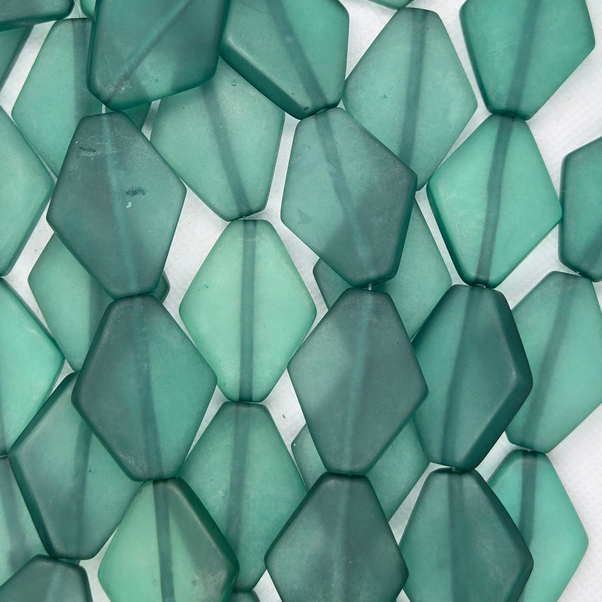 Light green diamond-shaped resin beads, close-up view of bead surfaces