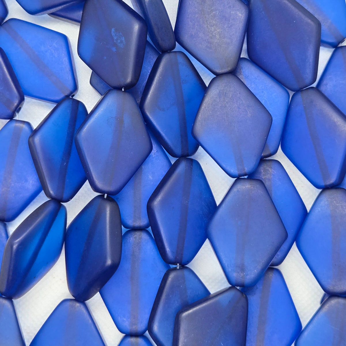 Diamond-shaped resin beads, deep blue, faceted surface, close-up