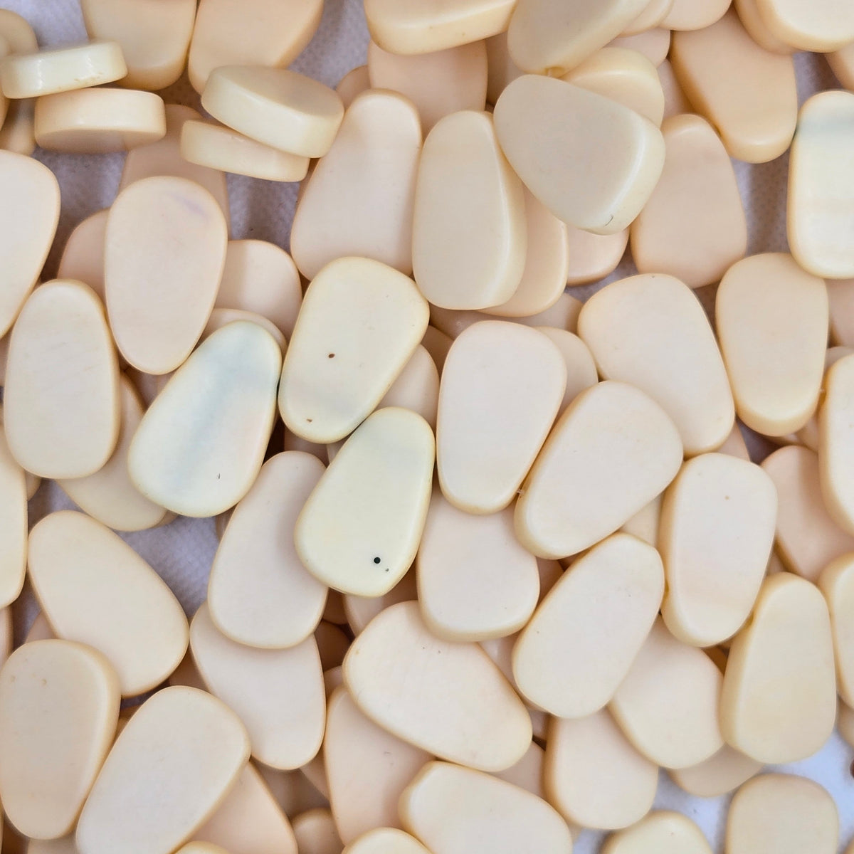 Beige teardrop resin beads with smooth surfaces, assorted sizes and shapes