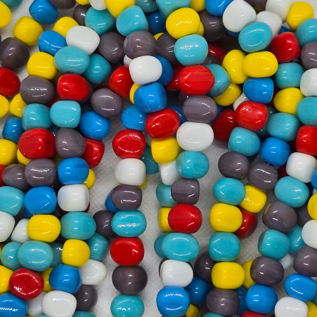 Round resin beads in multicolor mix of blue, yellow, white, red, and dark gray.