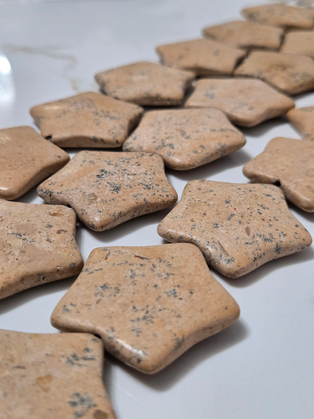 Assorted beige speckled star-shaped natural stone tiles, flat finish