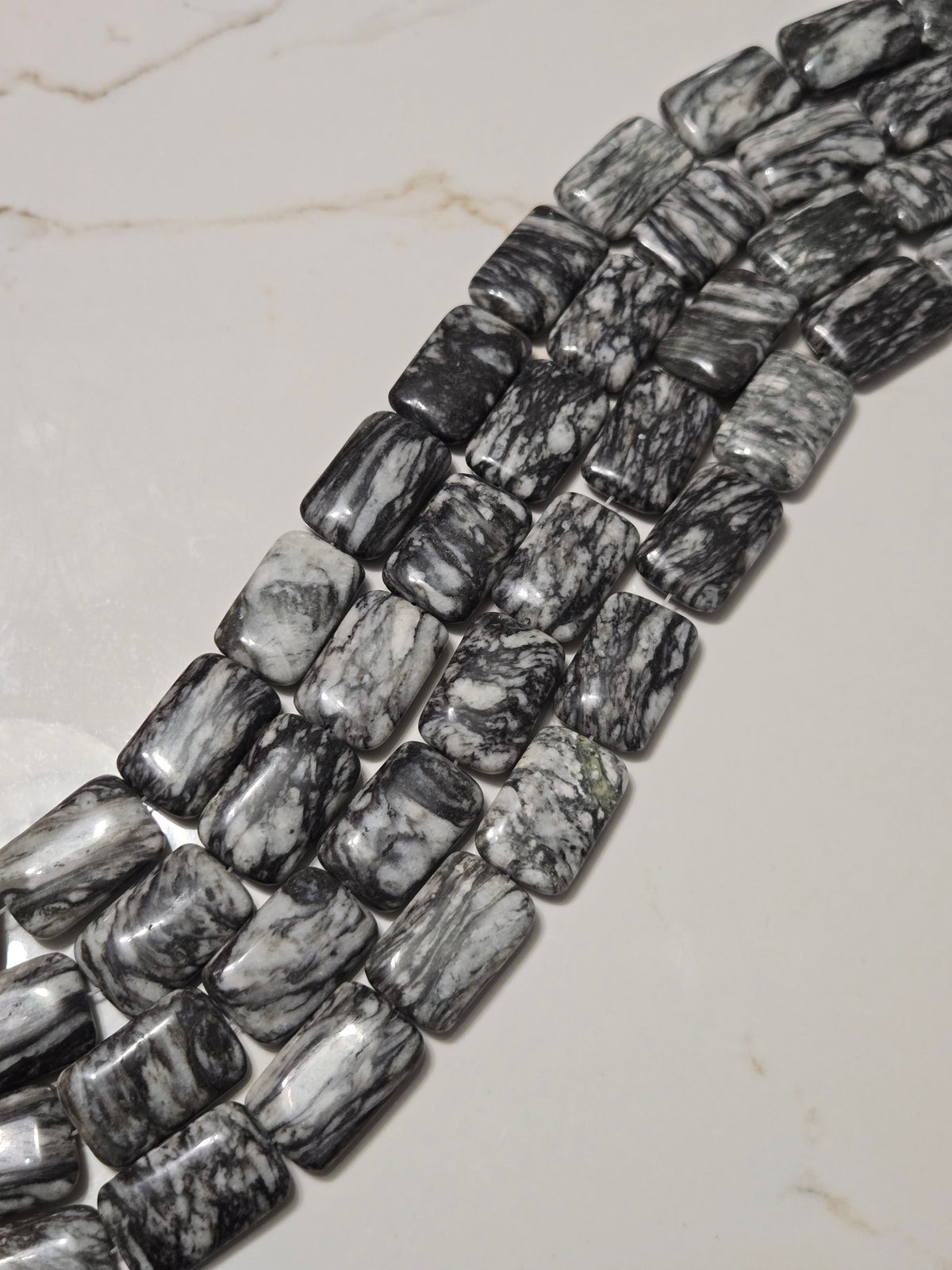 Pinolite rectangle stone pieces in a line, black-and-white marbled, approx. 2x4 cm