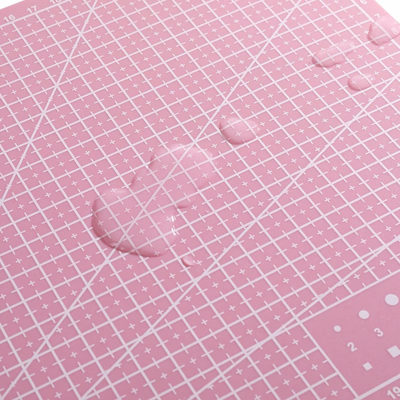 Pink self-healing cutting mat with white grid and measurement lines, close-up