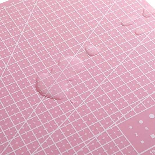 Pink self-healing cutting mat with white grid and measurement lines, close-up