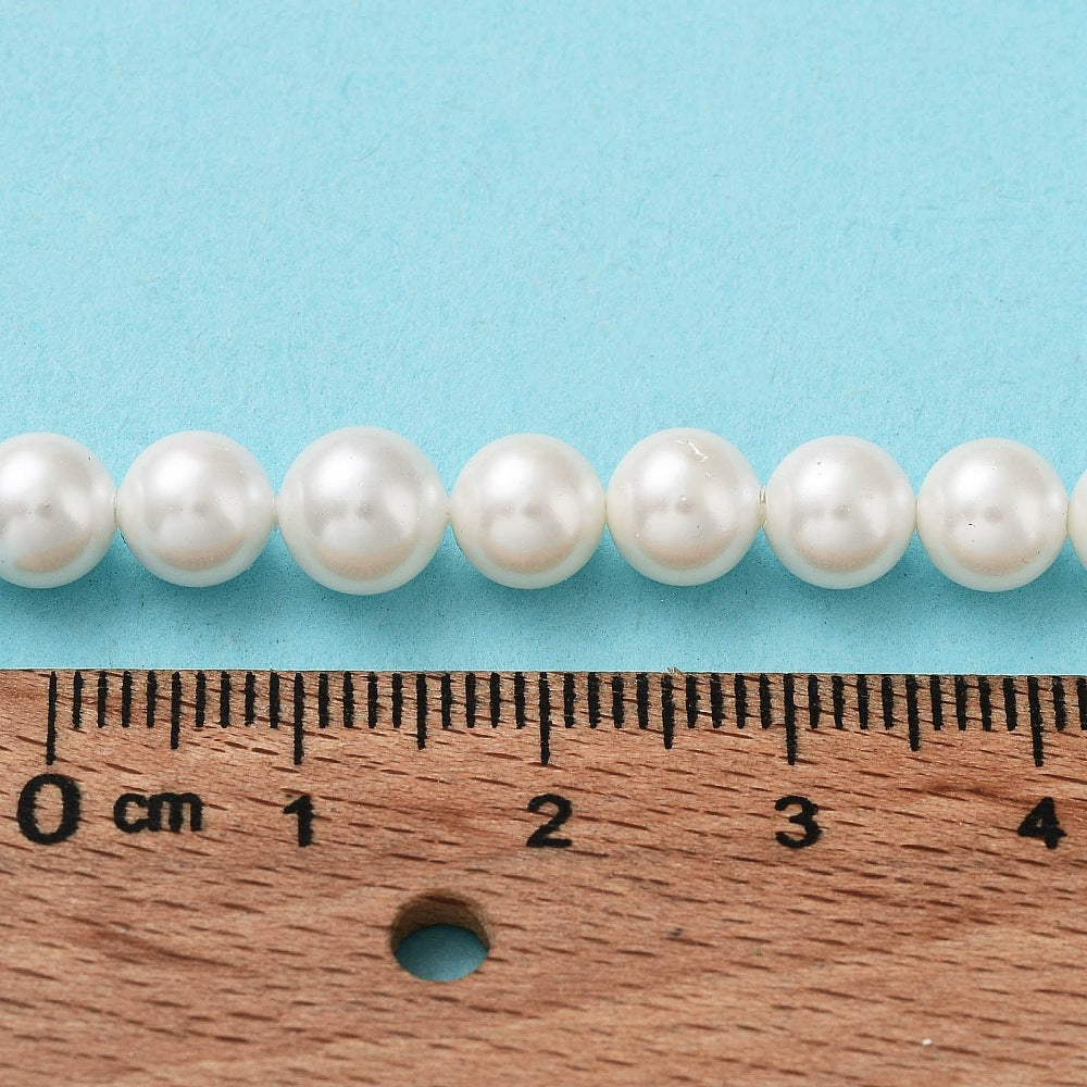 Round pearl beads strand laid along a 0–4 cm ruler