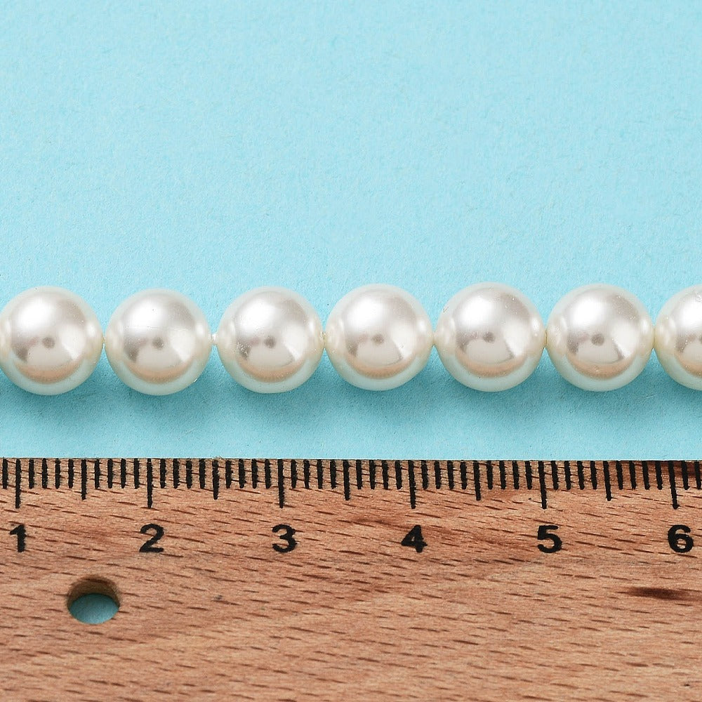Round white pearl beads strand laid next to a ruler for scale