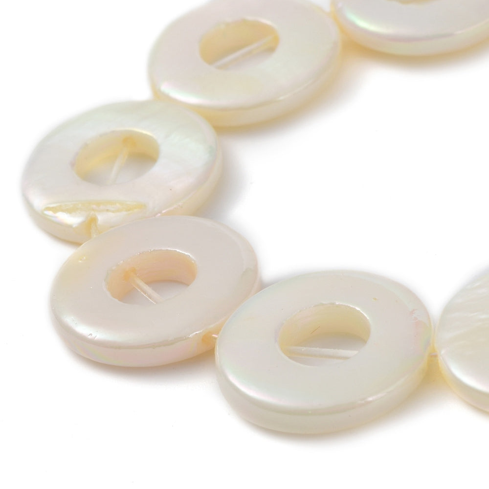Donut freshwater shell beads close-up, pearl white with warm yellow iridescent glow