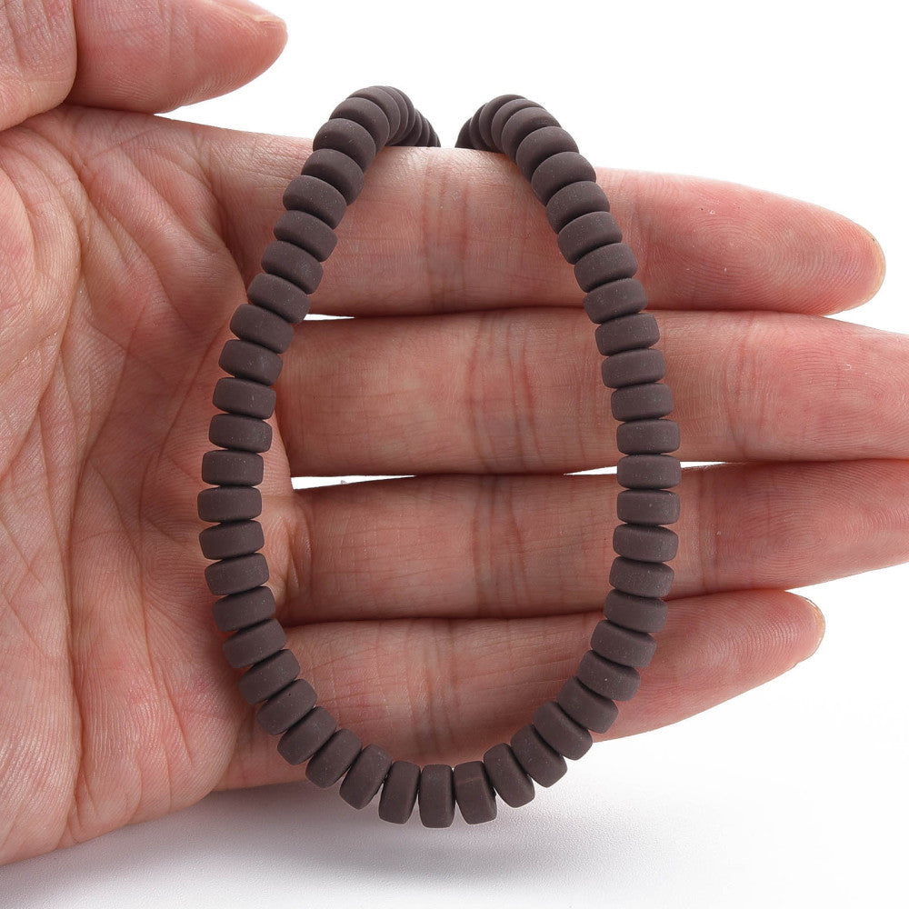 Flat round dark brown bead strand held in an open palm, matte finish