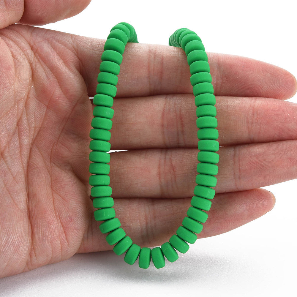 Green flat round bead strand held in hand, ridged discs with center holes