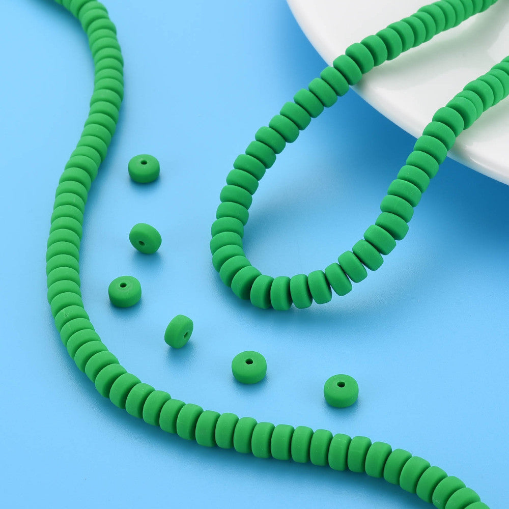 Green flat round bead strand with scattered beads, ridged discs with holes