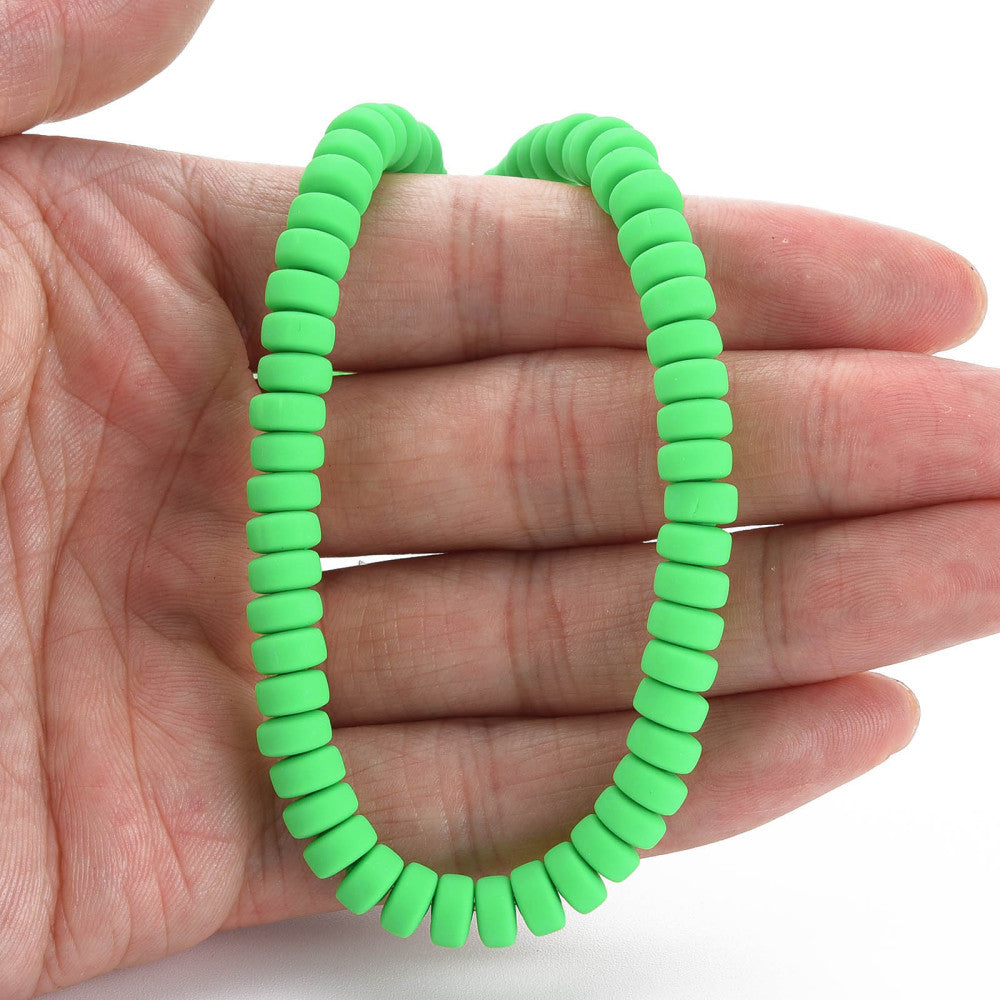 Lime green flat round polymer clay bead strand held in a hand, circular loop