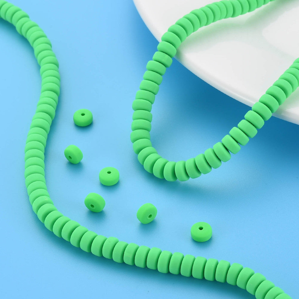 Lime green flat round polymer clay bead strand with several loose beads nearby