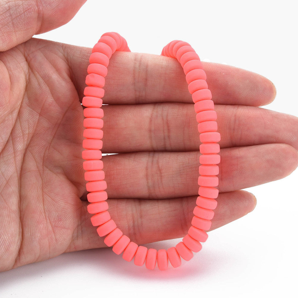 Flat round polymer clay bead strand in tomato red held in hand, small disc beads
