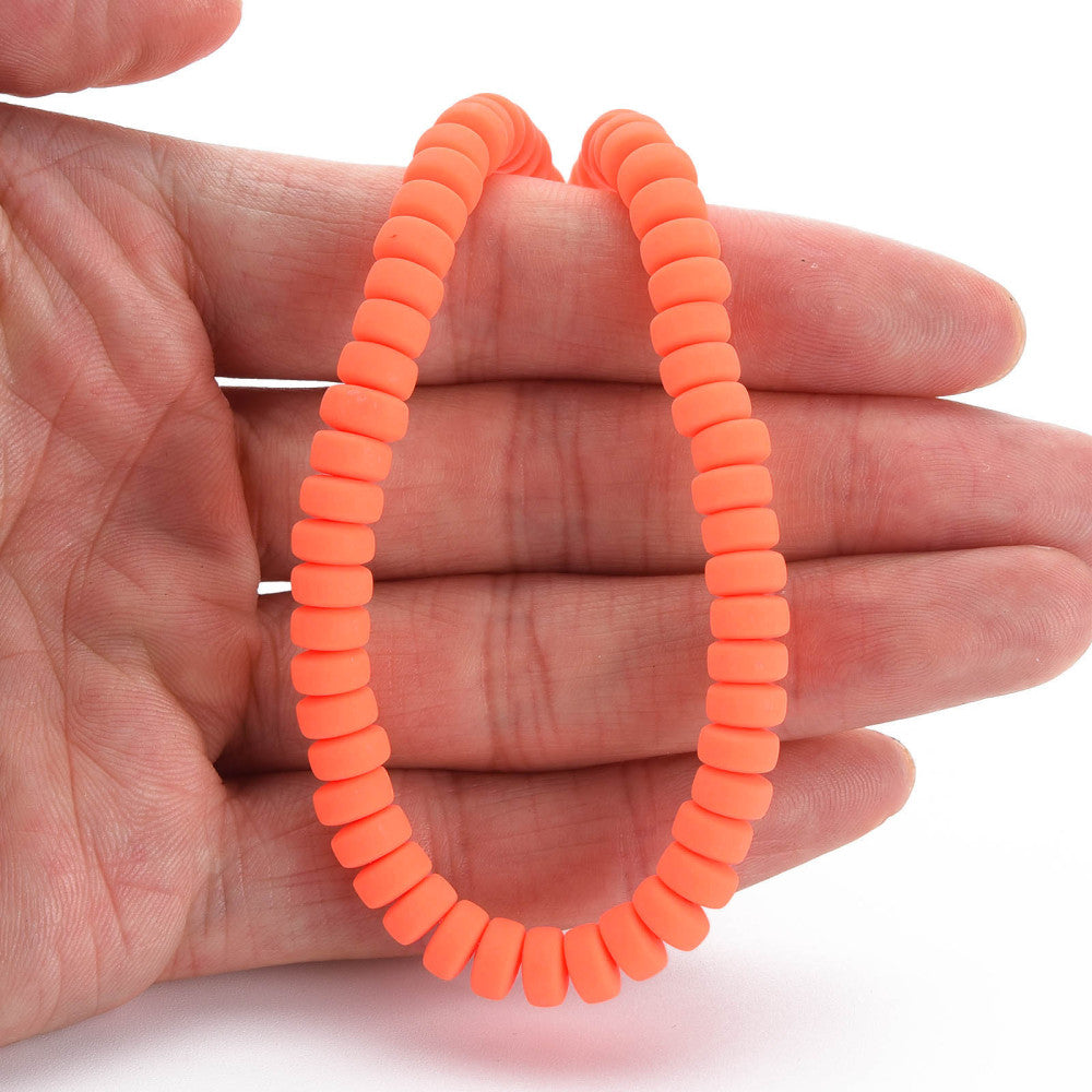 Orange-red flat round polymer clay bead strand held in a hand, loop shape