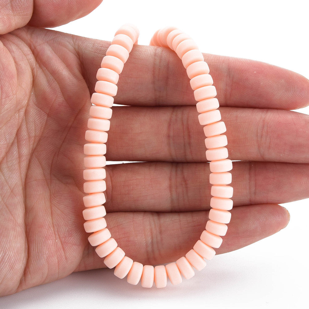 Flat round bead strand in pale pink, ridged discs held in hand