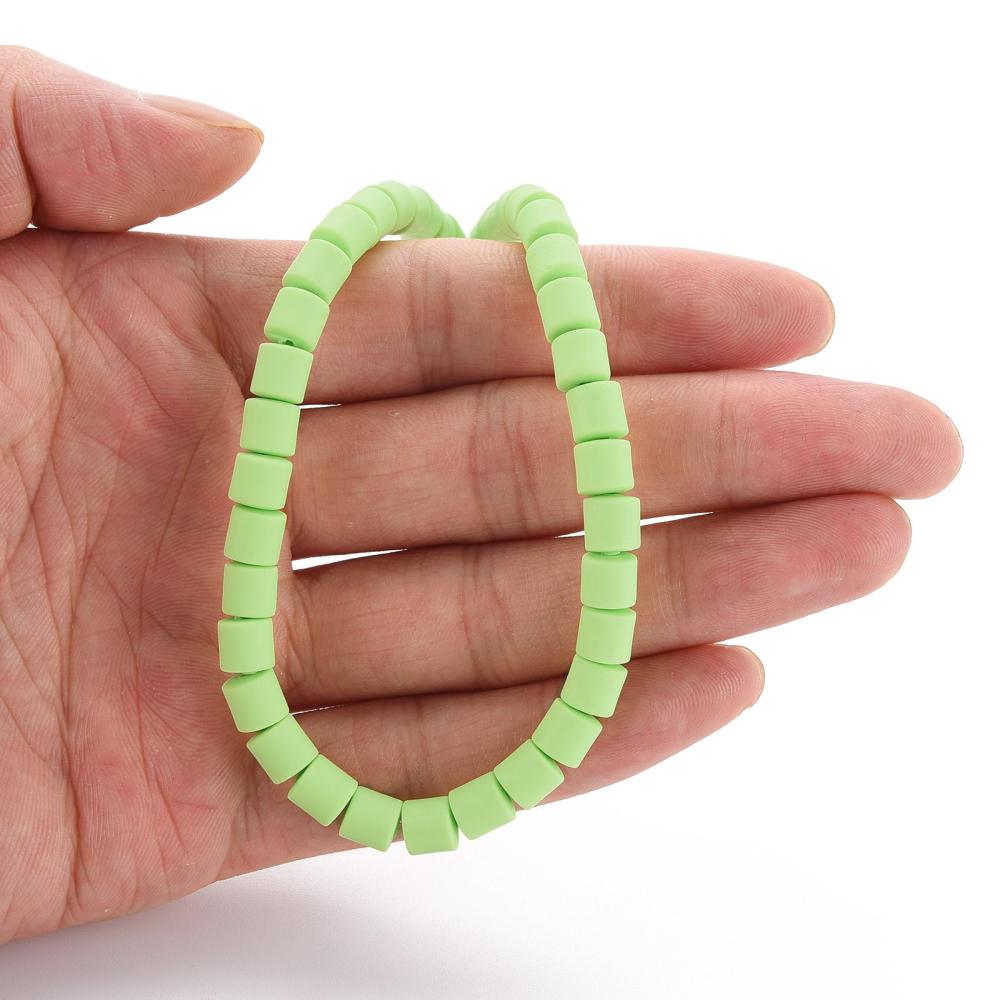 Pale green polymer clay column bead strand held in hands, oval looped shape
