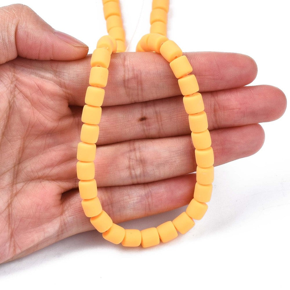 Orange polymer clay bead strand of 6mm tube beads held in a hand