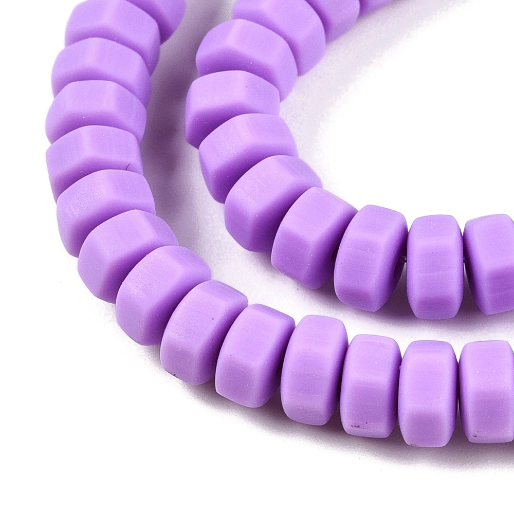 Close-up of purple hexagon polymer clay beads with central holes on a strand