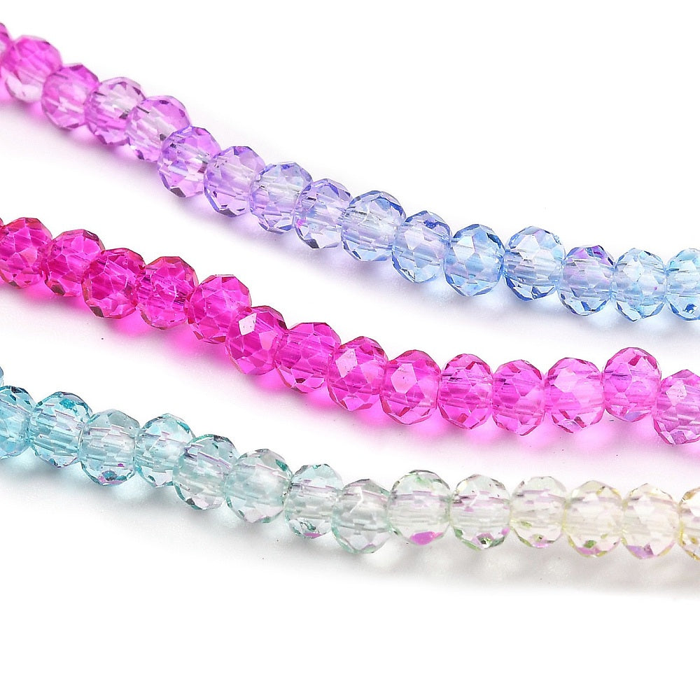 Faceted glass rondelle bead strands laid out: fuchsia, light blue, and clear mix
