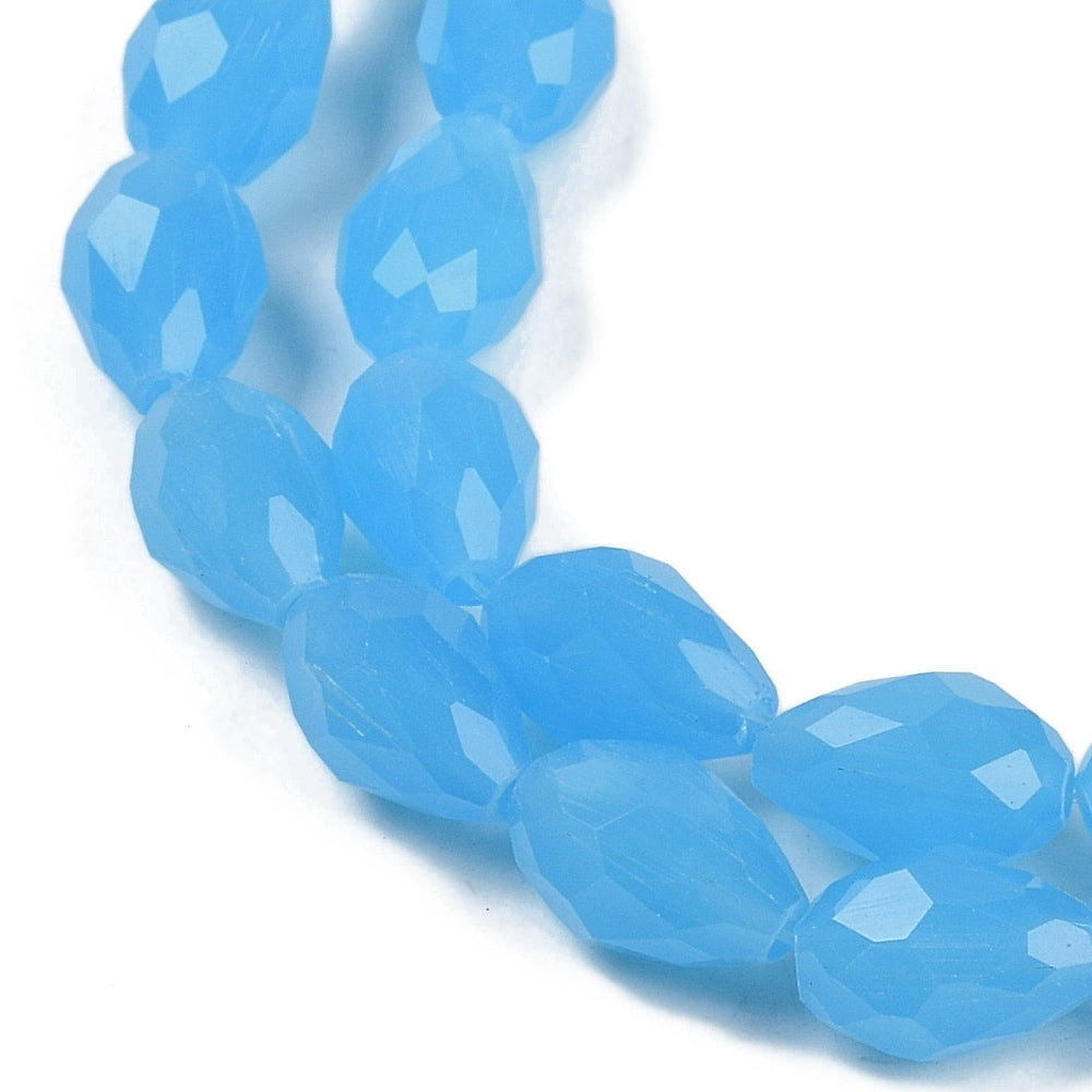 Blue faceted teardrop glass beads on a strand, angled close-up