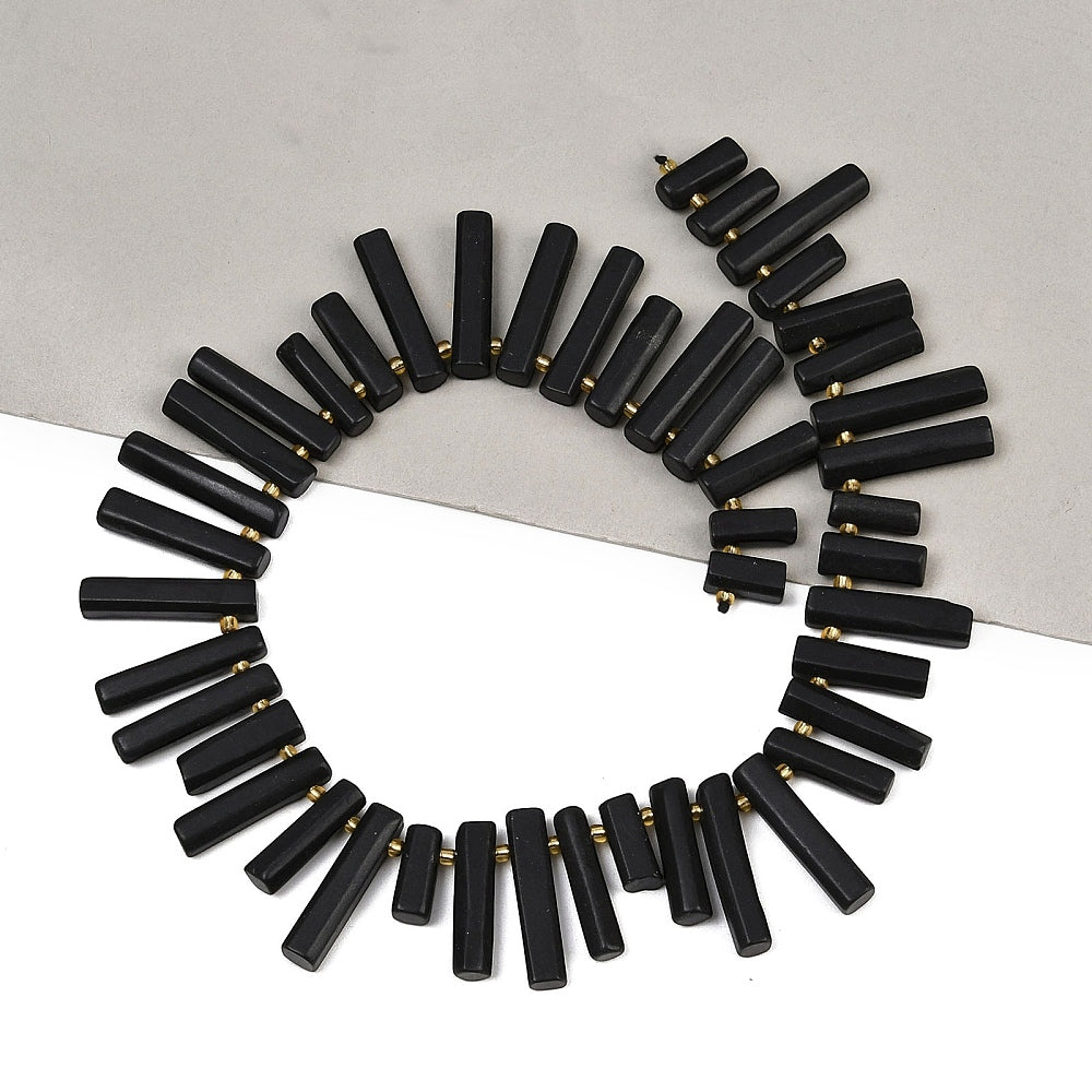 Circular arrangement of black column beads with gold-tone rings