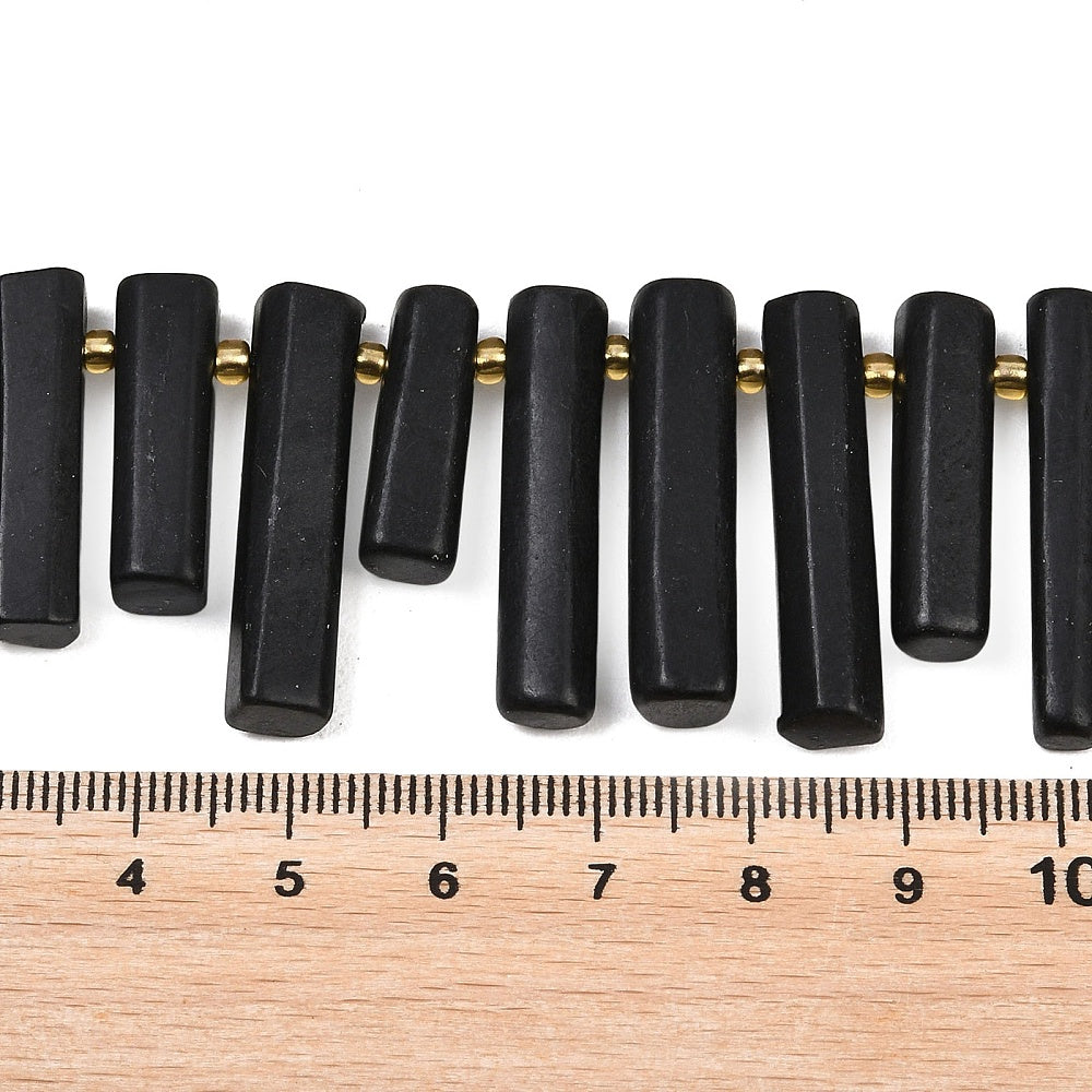 Black column beads on strand with gold-tone rings; size shown with ruler