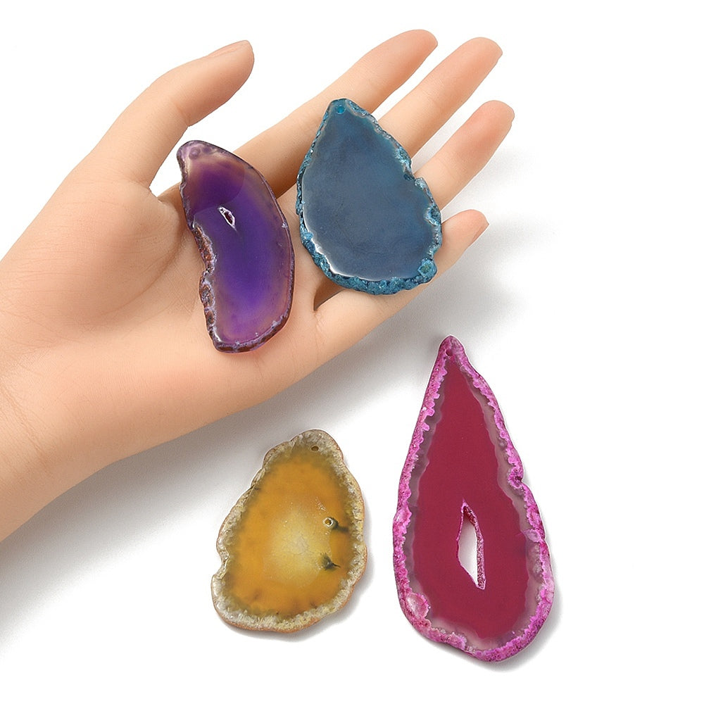 Agate pendant slices in purple, blue, yellow and magenta on open palm