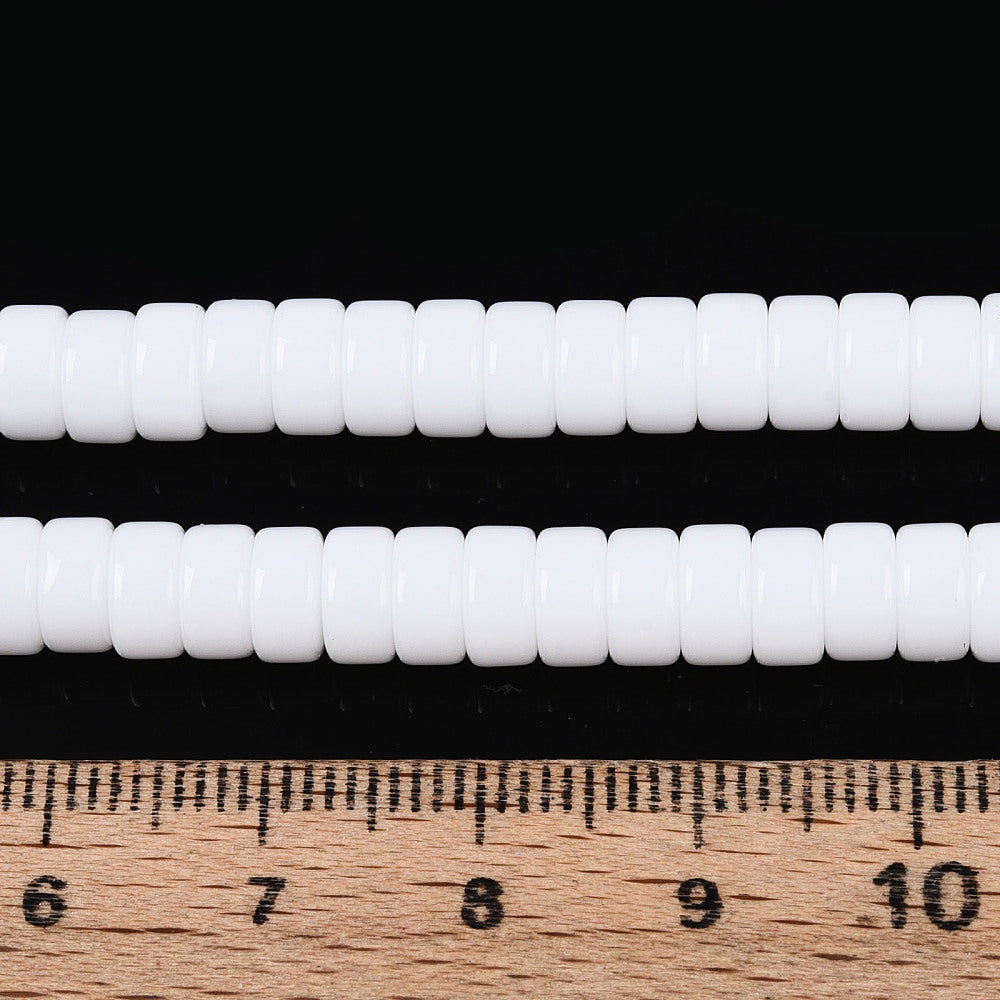 White opaque glass flat round beads strand beside ruler, approx 6mm disc beads
