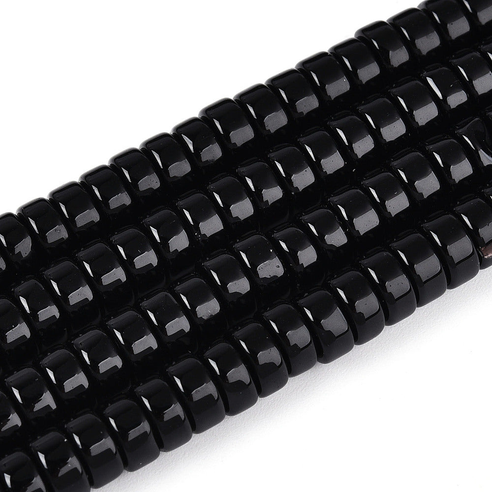 Close-up of black opaque glass flat round beads with glossy highlights