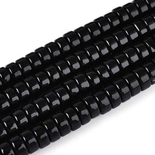 Close-up of black opaque glass flat round beads with glossy highlights