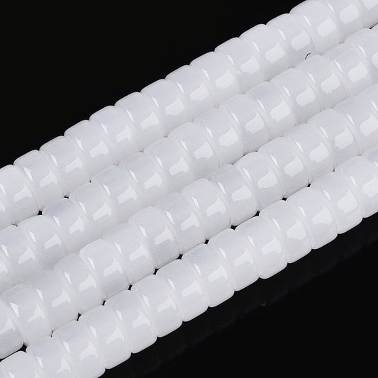 White flat round glass beads strand, close-up with faceted bead texture