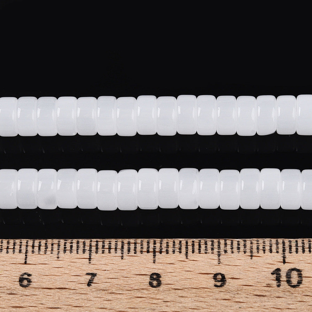 White flat round beads strand beside ruler, showing bead size