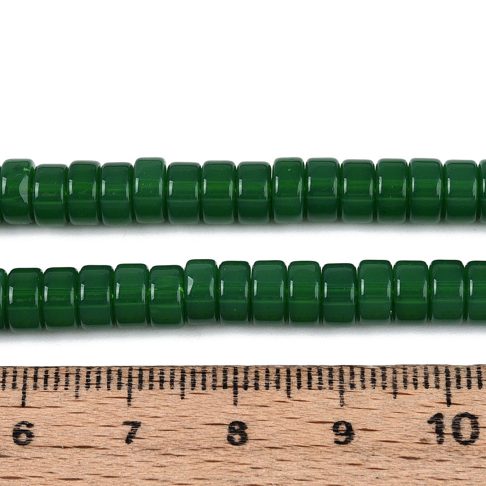 Green round bead strand beside measuring ruler, glossy beads, uniform size