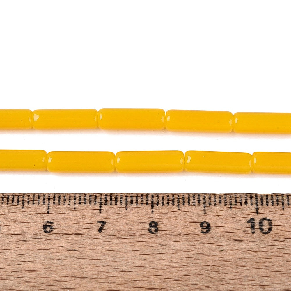 Gold yellow bugle beads on a strand with ruler for size reference