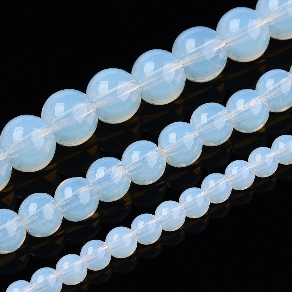 Transparent glass round beads strand, light blue opal-like, diagonal close-up of beads