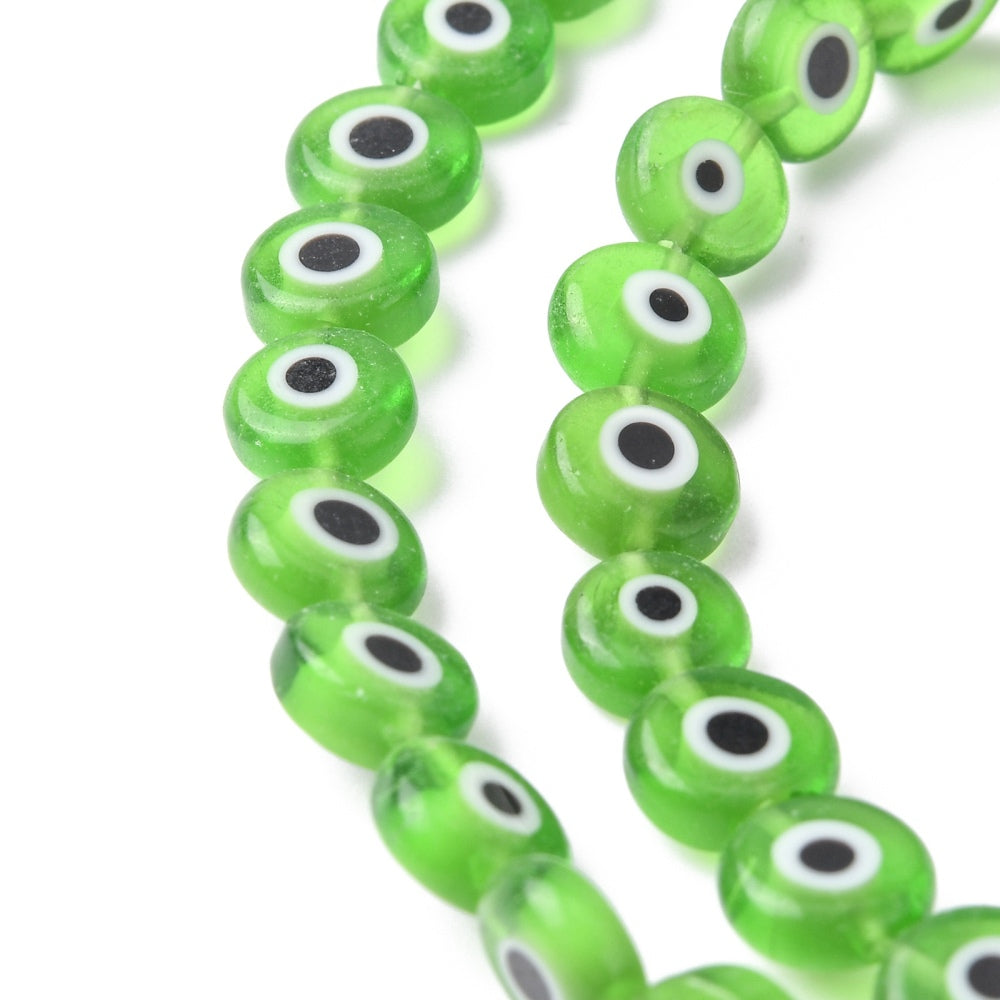Close-up of lime green flat round lampwork beads with white and black evil-eye centers